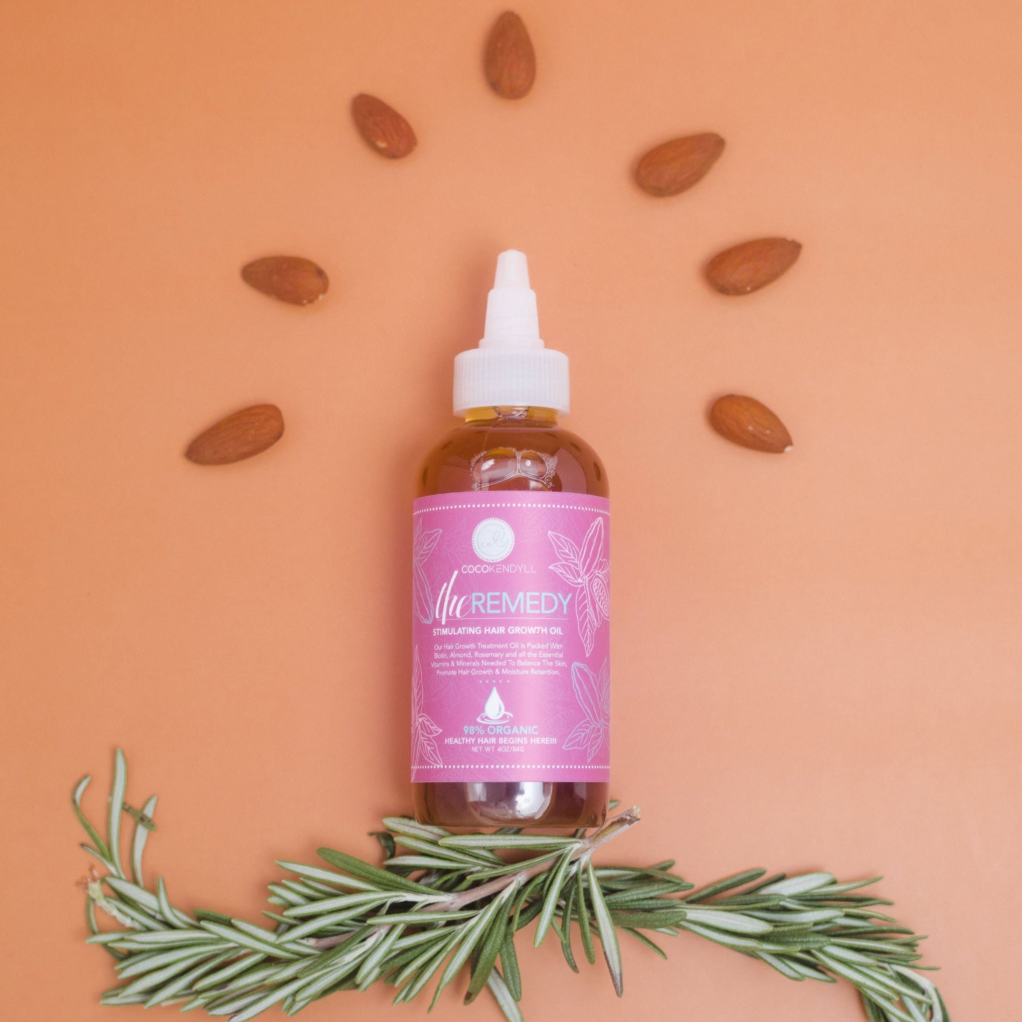Coco Kendyll Growth Oil bottle styled with almonds and rosemary, nourishing scalp oil with biotin